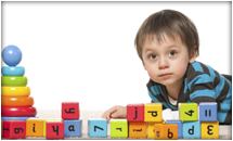 Toddler boy playing with blocks and looking at camera.