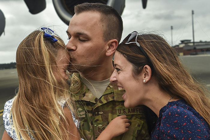 Father celebrating return from deployment with wife and daughter